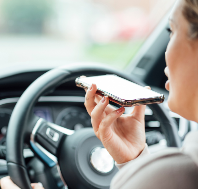 A person uses a smartphone while driving, indicating hands-free communication