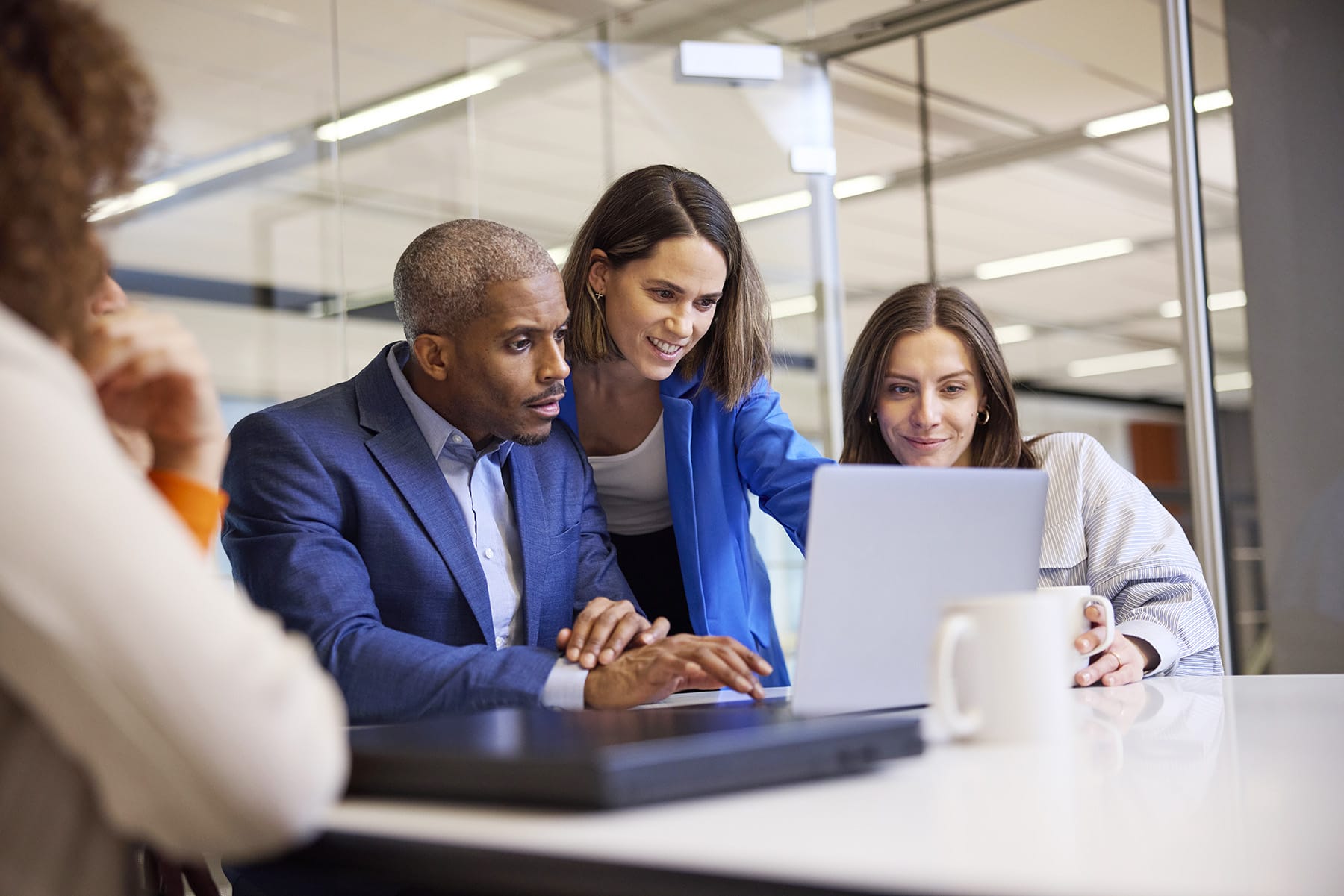 A team collaborates on a laptop in a modern office setting, discussing ideas and projects